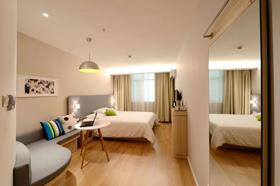 A couple wrapping furniture in a bright apartment, preparing to move.
